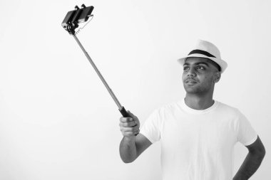 Siyah ve beyaz arka planda tatil için hazır şapkalı genç Hintli turistin stüdyo fotoğrafı.