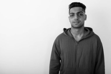 Siyah ve beyaz arka planda beyaz kapüşonlu genç Hintli adamın stüdyo fotoğrafı.