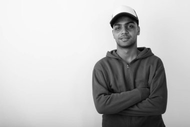 Siyah ve beyaz arka planda beyaz kapüşonlu genç Hintli adamın stüdyo fotoğrafı.