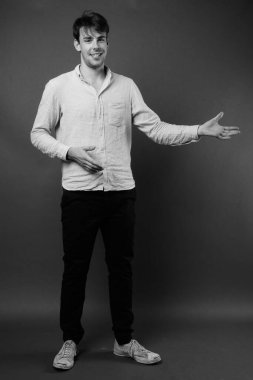 Siyah-beyaz gri arka planda genç yakışıklı adamın stüdyo çekimi