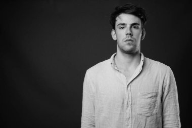 Siyah-beyaz gri arka planda genç yakışıklı adamın stüdyo çekimi