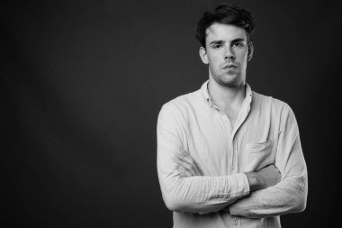 Siyah-beyaz gri arka planda genç yakışıklı adamın stüdyo çekimi