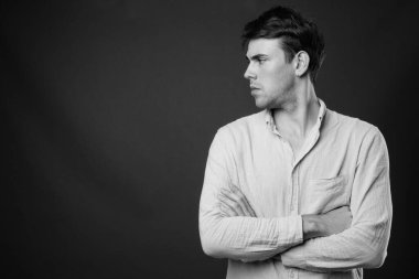 Siyah-beyaz gri arka planda genç yakışıklı adamın stüdyo çekimi