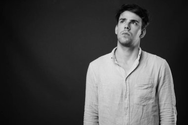 Siyah-beyaz gri arka planda genç yakışıklı adamın stüdyo çekimi