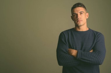 Renkli arka planda süveter giyen genç bir adamın stüdyo fotoğrafı.