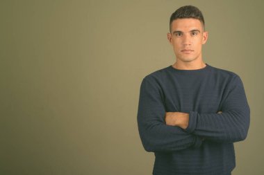 Renkli arka planda süveter giyen genç bir adamın stüdyo fotoğrafı.