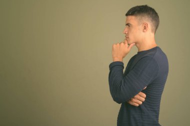 Renkli arka planda süveter giyen genç bir adamın stüdyo fotoğrafı.