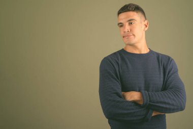 Renkli arka planda süveter giyen genç bir adamın stüdyo fotoğrafı.