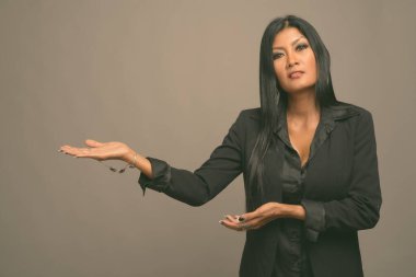 Asyalı güzel bir iş kadınının gri arka planda çekilmiş bir stüdyo fotoğrafı.