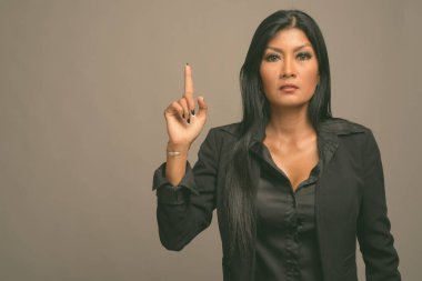 Asyalı güzel bir iş kadınının gri arka planda çekilmiş bir stüdyo fotoğrafı.