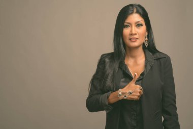 Asyalı güzel bir iş kadınının gri arka planda çekilmiş bir stüdyo fotoğrafı.