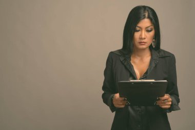 Asyalı güzel bir iş kadınının gri arka planda çekilmiş bir stüdyo fotoğrafı.