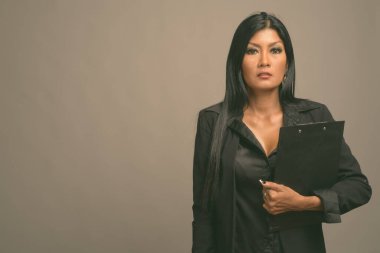 Asyalı güzel bir iş kadınının gri arka planda çekilmiş bir stüdyo fotoğrafı.