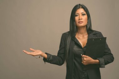 Asyalı güzel bir iş kadınının gri arka planda çekilmiş bir stüdyo fotoğrafı.