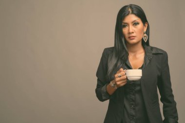 Asyalı güzel bir iş kadınının gri arka planda çekilmiş bir stüdyo fotoğrafı.