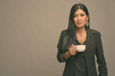 Asyalı güzel bir iş kadınının gri arka planda çekilmiş bir stüdyo fotoğrafı.