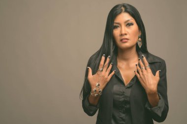 Asyalı güzel bir iş kadınının gri arka planda çekilmiş bir stüdyo fotoğrafı.