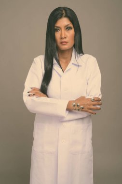 Olgun, güzel Asyalı kadın doktorun gri arka planda çekilmiş bir fotoğrafı.
