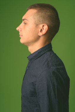 Yeşil arka planda mavi gömlekli genç ve yakışıklı işadamının stüdyo fotoğrafı.