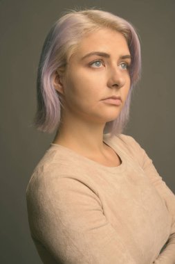 Stüdyo çekimlerinde, gri arka planda renkli saçlı güzel asi kadın görülüyor.