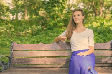 Parkta dinlenen uzun sarı saçlı güzel bir kadının portresi.