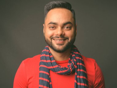 Gri arka planda genç sakallı Hintli adamın stüdyo fotoğrafı.