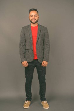 Genç sakallı Hintli işadamının gri arka planda çekilmiş bir fotoğrafı.