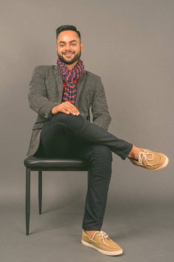 Genç sakallı Hintli işadamının gri arka planda çekilmiş bir fotoğrafı.