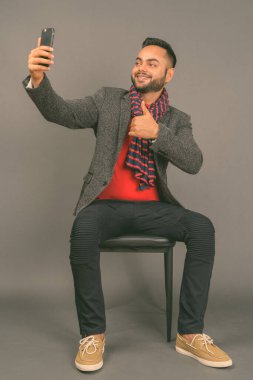 Genç sakallı Hintli işadamının gri arka planda çekilmiş bir fotoğrafı.