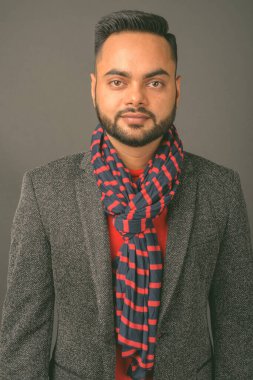 Genç sakallı Hintli işadamının gri arka planda çekilmiş bir fotoğrafı.