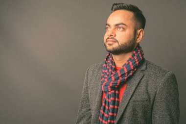 Genç sakallı Hintli işadamının gri arka planda çekilmiş bir fotoğrafı.