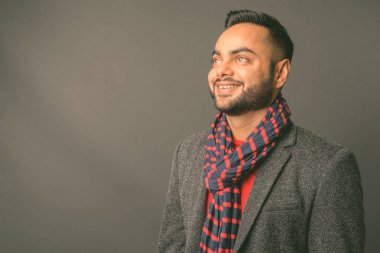 Genç sakallı Hintli işadamının gri arka planda çekilmiş bir fotoğrafı.