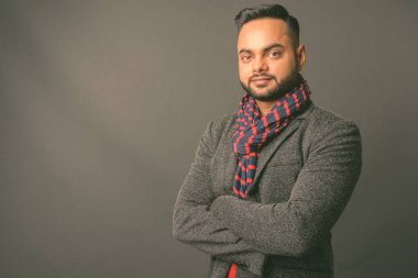 Genç sakallı Hintli işadamının gri arka planda çekilmiş bir fotoğrafı.