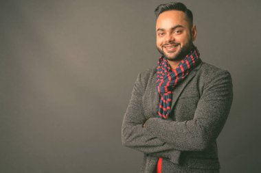Genç sakallı Hintli işadamının gri arka planda çekilmiş bir fotoğrafı.