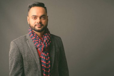 Genç sakallı Hintli işadamının gri arka planda çekilmiş bir fotoğrafı.