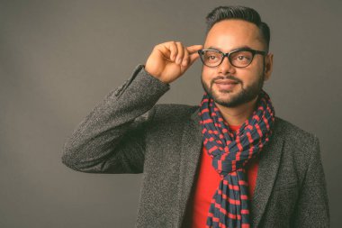 Genç sakallı Hintli işadamının gri arka planda çekilmiş bir fotoğrafı.