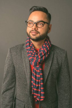 Genç sakallı Hintli işadamının gri arka planda çekilmiş bir fotoğrafı.