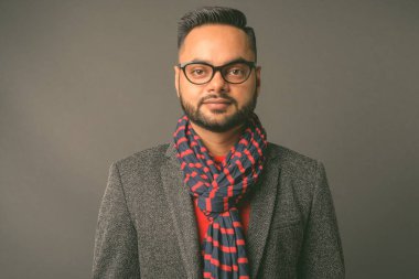 Genç sakallı Hintli işadamının gri arka planda çekilmiş bir fotoğrafı.