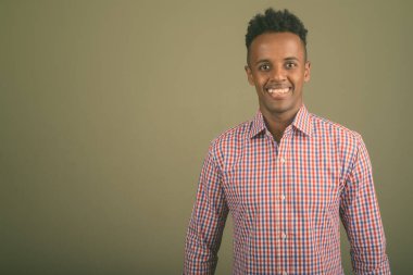 Renkli arka planda mor kareli gömlek giyen yakışıklı Afrikalı iş adamının stüdyo fotoğrafı.