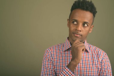 Renkli arka planda mor kareli gömlek giyen yakışıklı Afrikalı iş adamının stüdyo fotoğrafı.