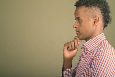 Renkli arka planda mor kareli gömlek giyen yakışıklı Afrikalı iş adamının stüdyo fotoğrafı.