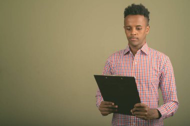 Renkli arka planda mor kareli gömlek giyen yakışıklı Afrikalı iş adamının stüdyo fotoğrafı.