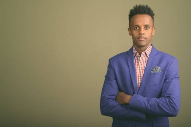 Renkli arka planda takım elbise giyen genç ve yakışıklı Afrikalı işadamının stüdyo fotoğrafı.