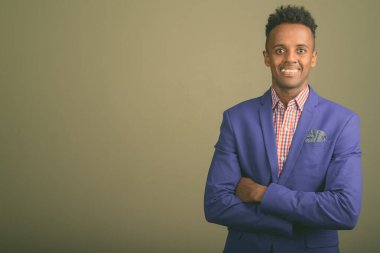 Renkli arka planda takım elbise giyen genç ve yakışıklı Afrikalı işadamının stüdyo fotoğrafı.