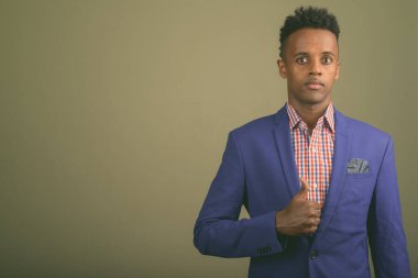 Renkli arka planda takım elbise giyen genç ve yakışıklı Afrikalı işadamının stüdyo fotoğrafı.