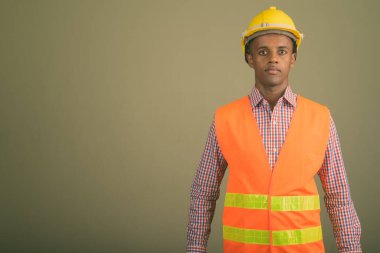 Genç Afrikalı yakışıklı inşaat işçisinin renkli arka planda çekilmiş bir fotoğrafı.
