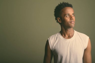 Renkli arka planda spor yapmaya hazır genç Afrikalı adamın stüdyo çekimi.