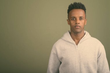 Renkli arka planda beyaz kapüşonlu genç Afrikalı adamın stüdyo fotoğrafı.
