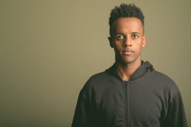 Renkli arka planda siyah kapüşonlu genç Afrikalı adamın stüdyo fotoğrafı.