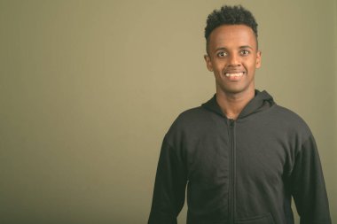 Renkli arka planda siyah kapüşonlu genç Afrikalı adamın stüdyo fotoğrafı.